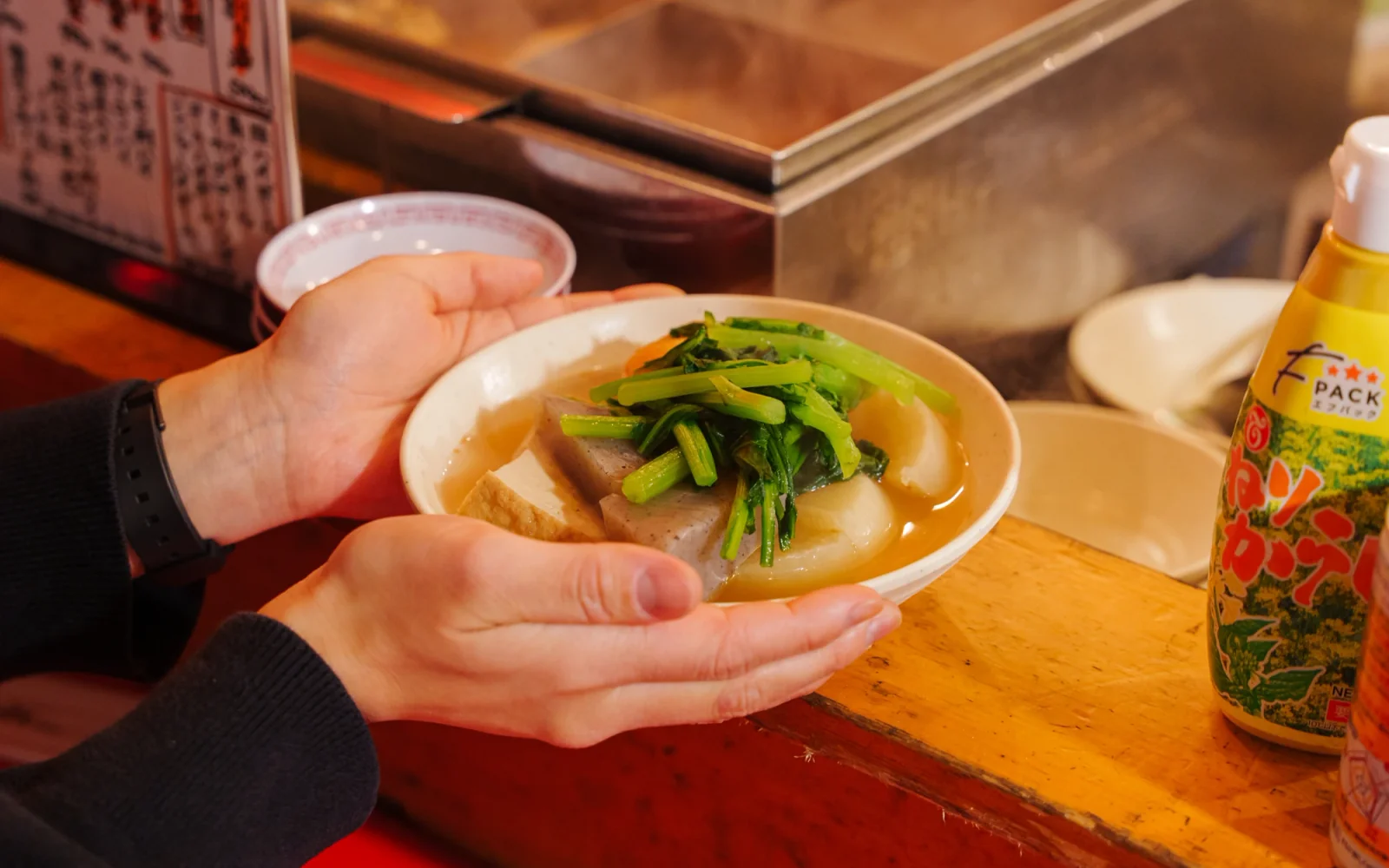 Deep ceramic oden vat at a Hakata Yatai filled with golden dashi, stewed daikon radishes, and fish cakes