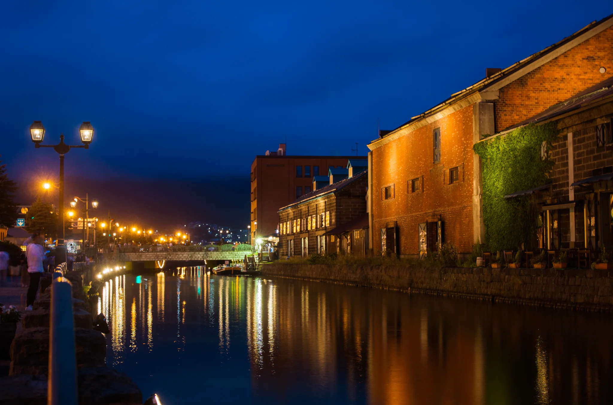 Winter twilight reflecting along Otaru Canal with historic brick and stone warehouses dusted in snow