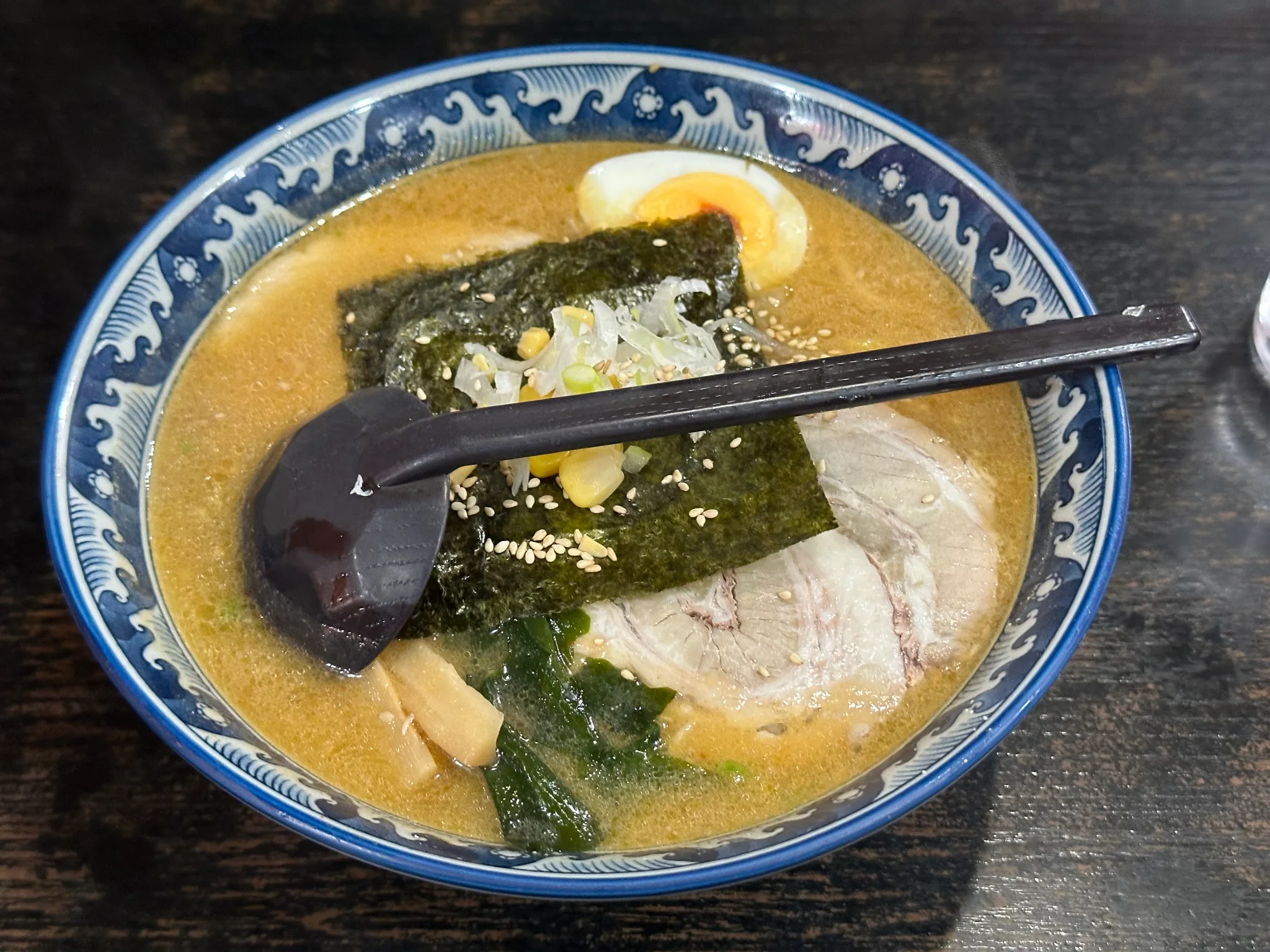 Steaming bowl of rich Sapporo miso ramen featuring curly yellow noodles, tender chashu, and sweet corn