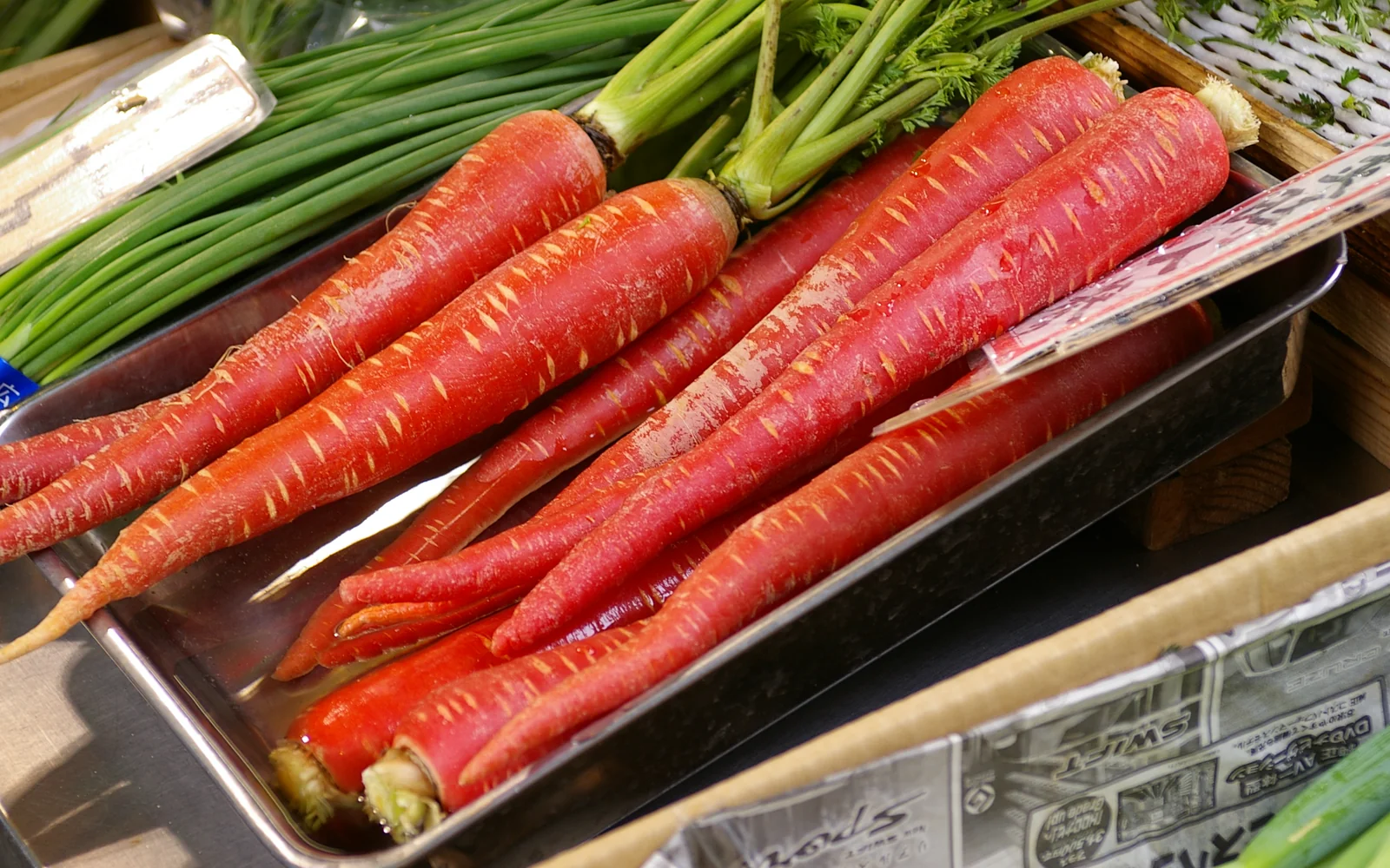 Slender crimson Kintoki carrots and seasonal winter roots displayed at Nishiki Market in Kyoto
