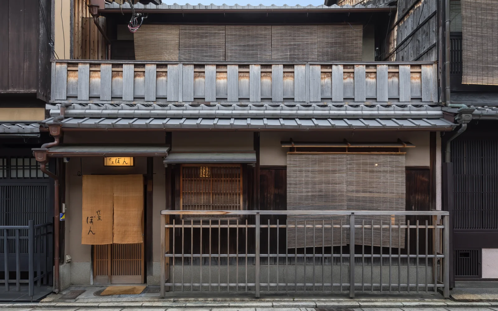 Traditional Kyoto Machiya wooden townhouse facade with fine koushi timber lattices and woven bamboo sudare