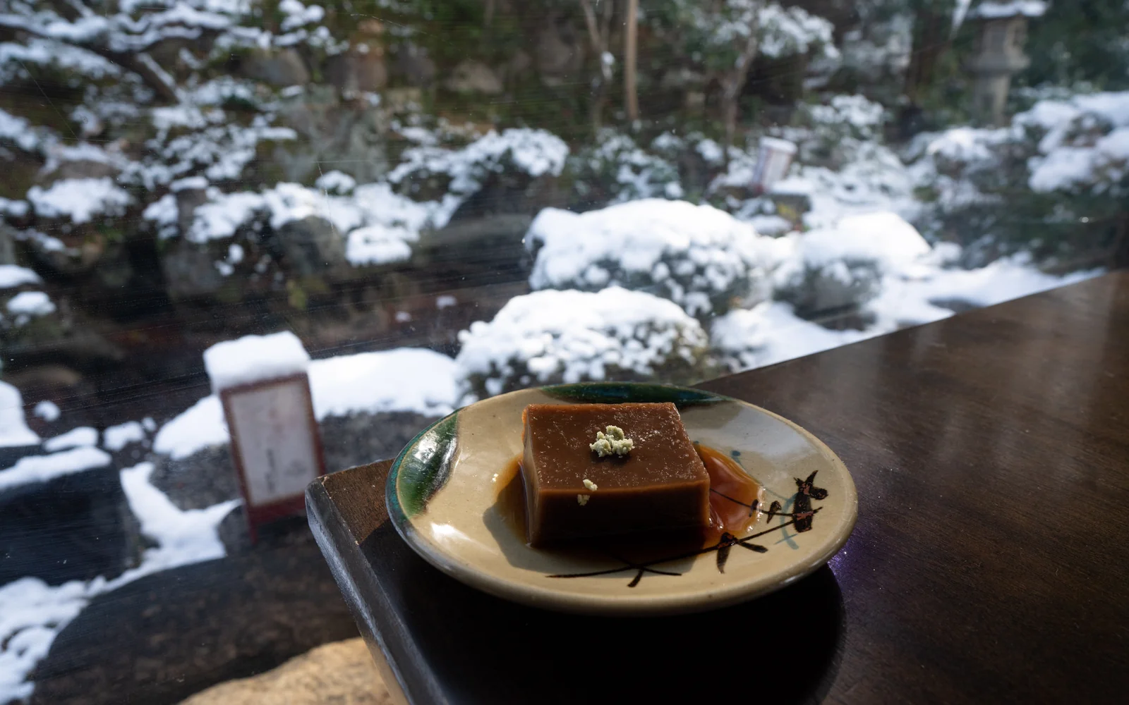 Silken handcrafted Goma-dofu sesame tofu resting against the snowy courtyard garden of Nanzen-ji Okutan